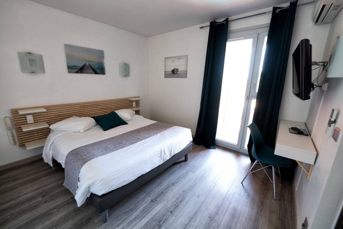 Une chambre à coucher moderne avec un lit, un bureau et un téléviseur.