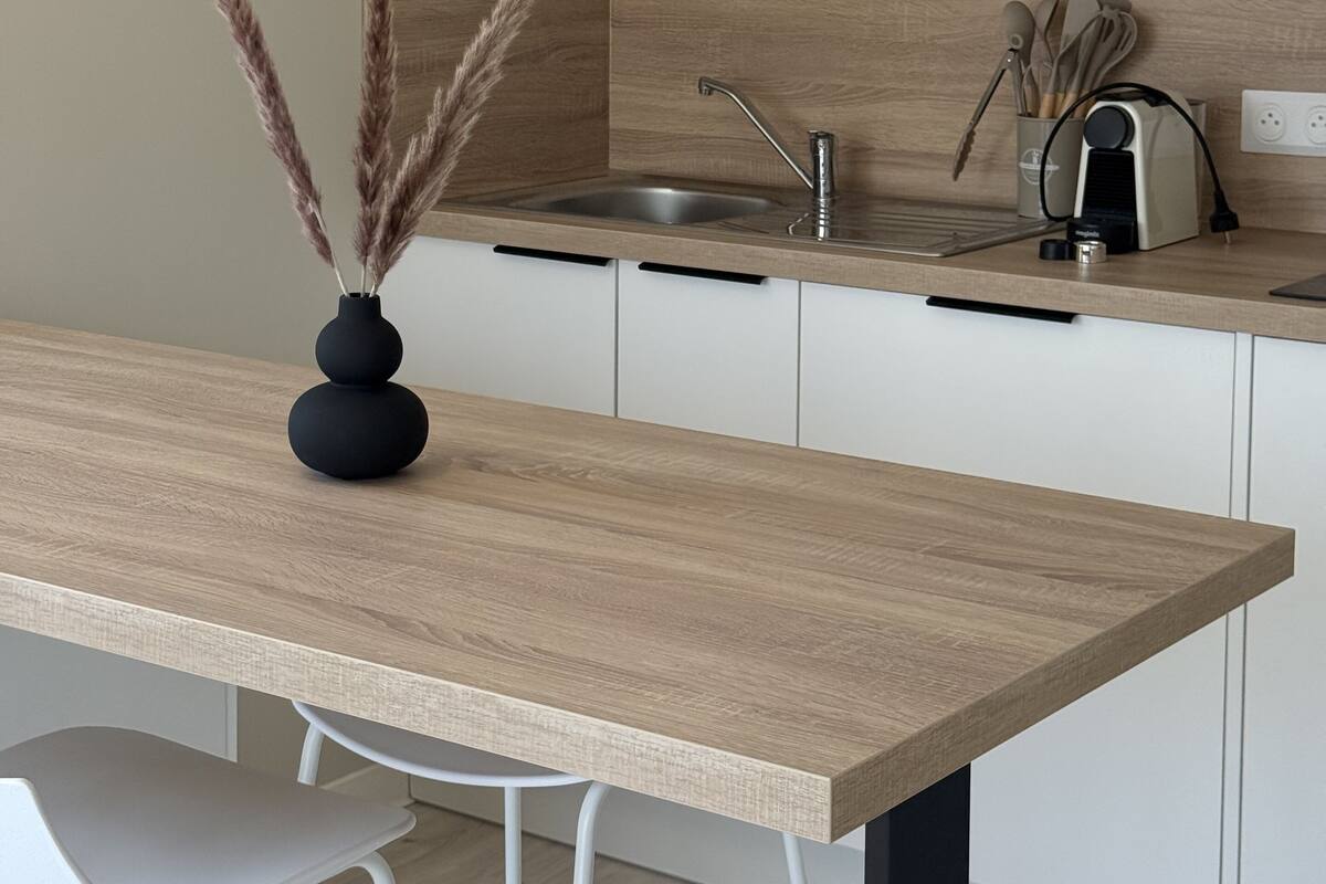 Une cuisine moderne avec un plan de travail en bois, un micro-ondes noir, un évier et un vase contenant de l’herbe des pampas.