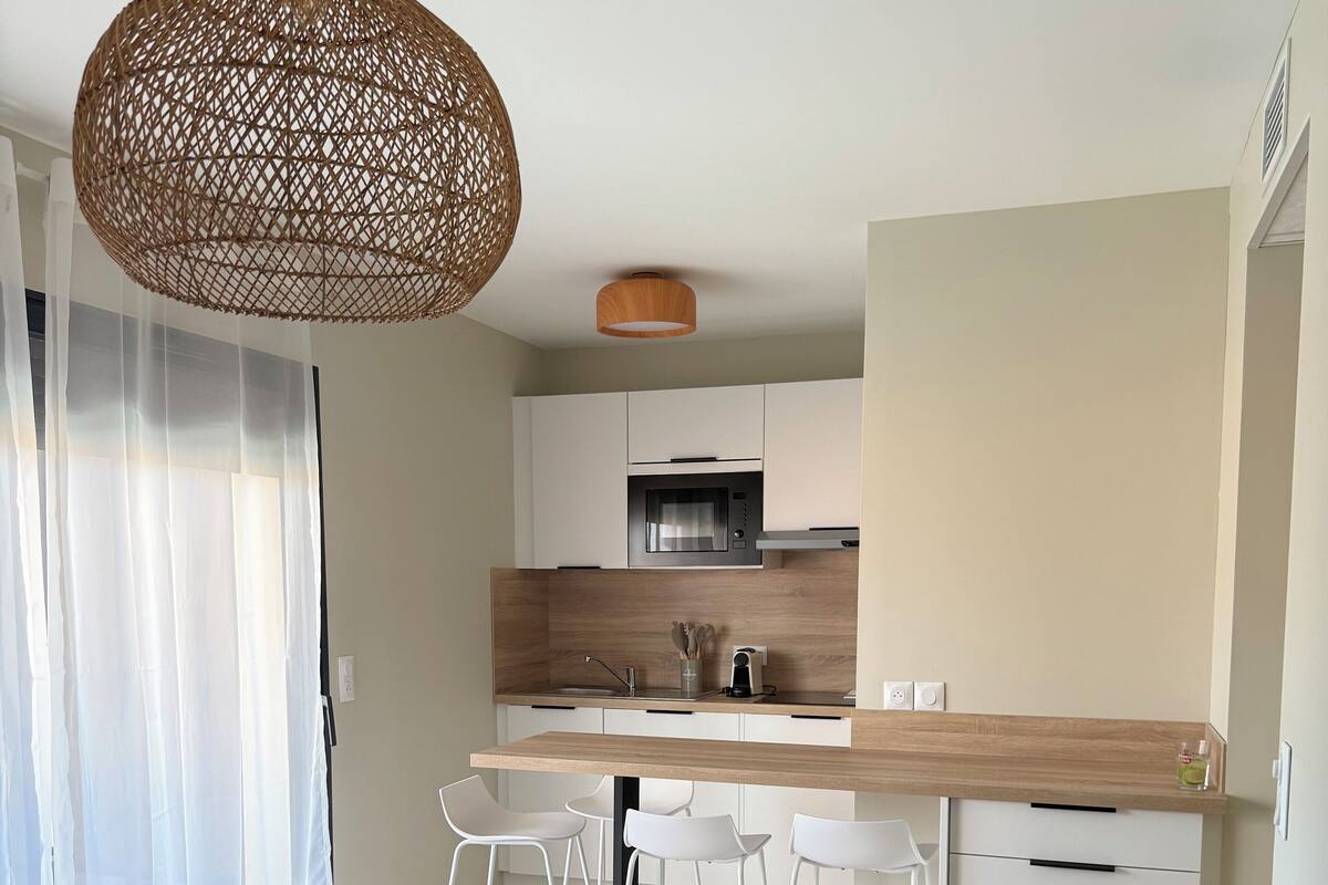 Une cuisine moderne et compacte, avec des meubles blancs et un four encastré.