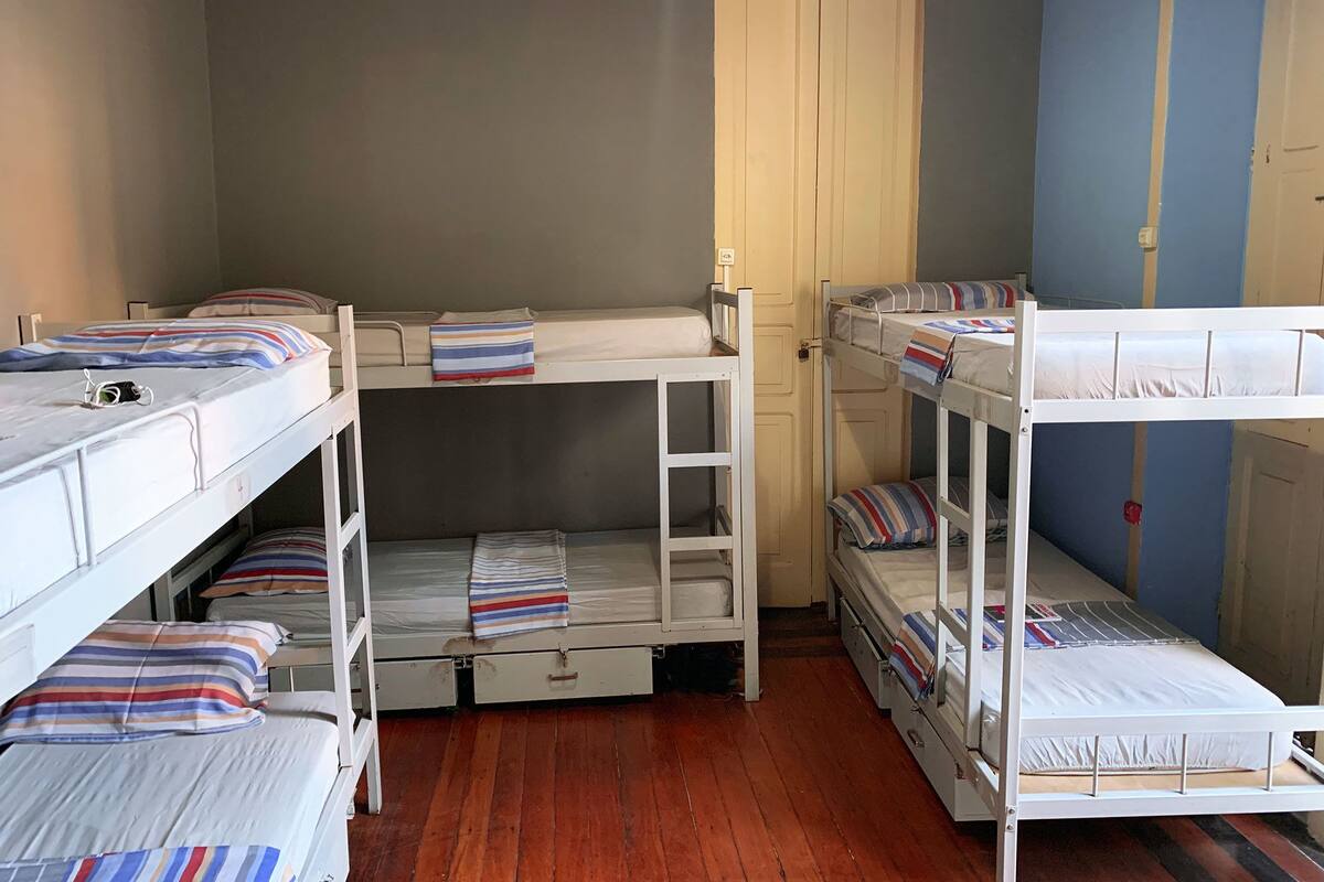 Une chambre de dortoir avec des lits superposés, un plancher en bois et une porte.