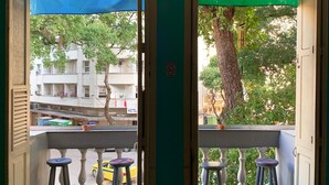 A view from a balcony with two flags, a street view with buildings, and a tree. - Massape Rio Hostel (Rio de Janeiro)