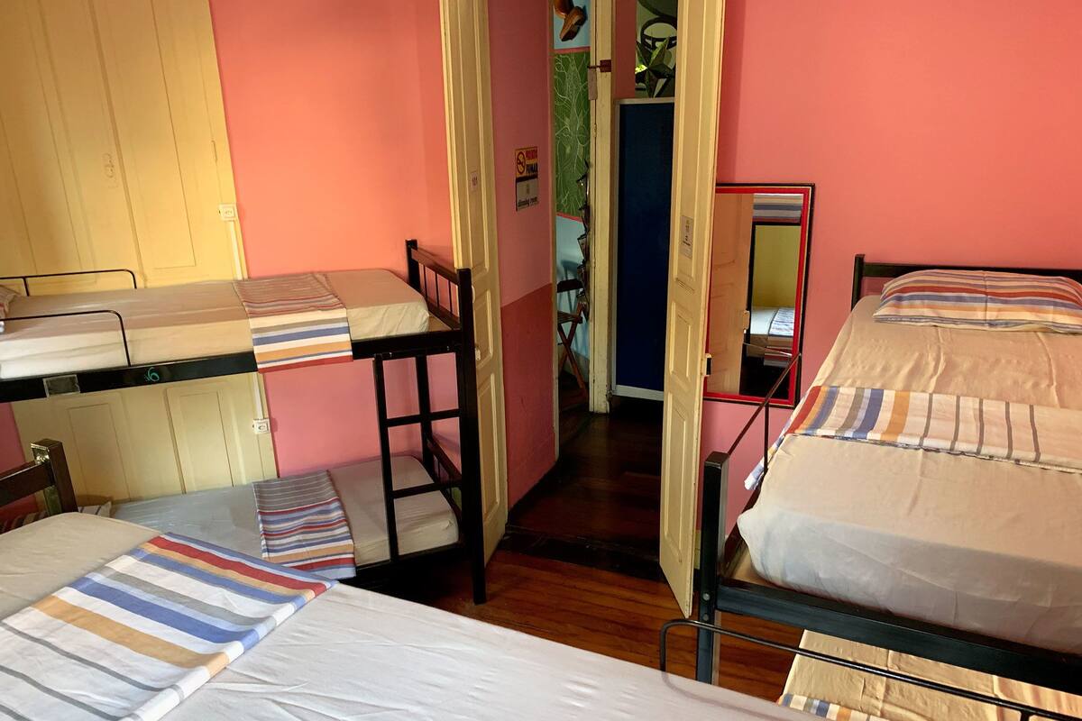 Une chambre de dortoir avec des lits superposés, une porte en bois et un miroir au mur.