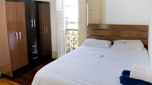 A hotel room with a bed, white linens, a wooden headboard, and a wardrobe with multiple drawers. - Massape Rio Hostel (Rio de Janeiro)