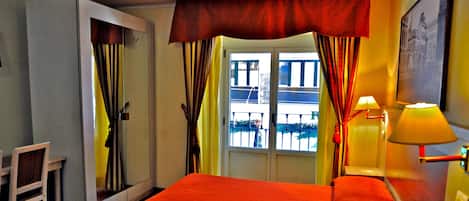 Une chambre d’hôtel avec un lit, un bureau, une chaise et une fenêtre avec des rideaux.