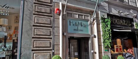 Hotel Rio Milano's exterior with a sign, a fire alarm, and decorative planters.
