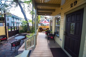 A covered outdoor patio with wicker furniture and a red umbrella.