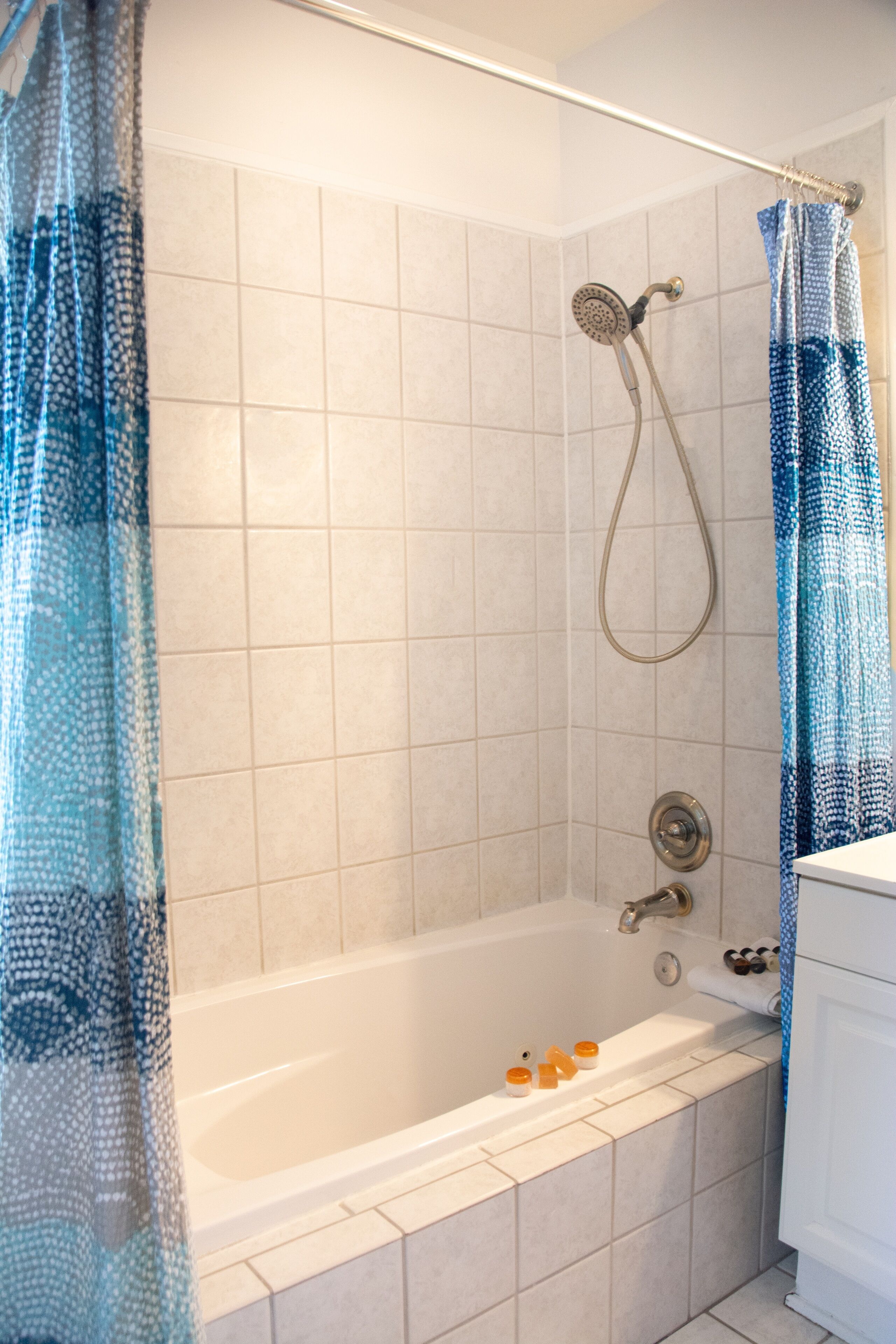 Een badkamer met een badkuip, douche en witte betegelde wanden.