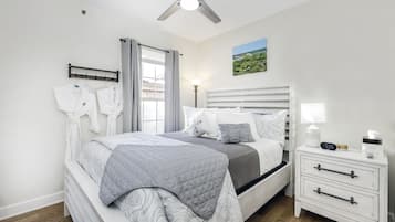 A bedroom with a bed, bedside table, nightstand, and a ceiling fan.