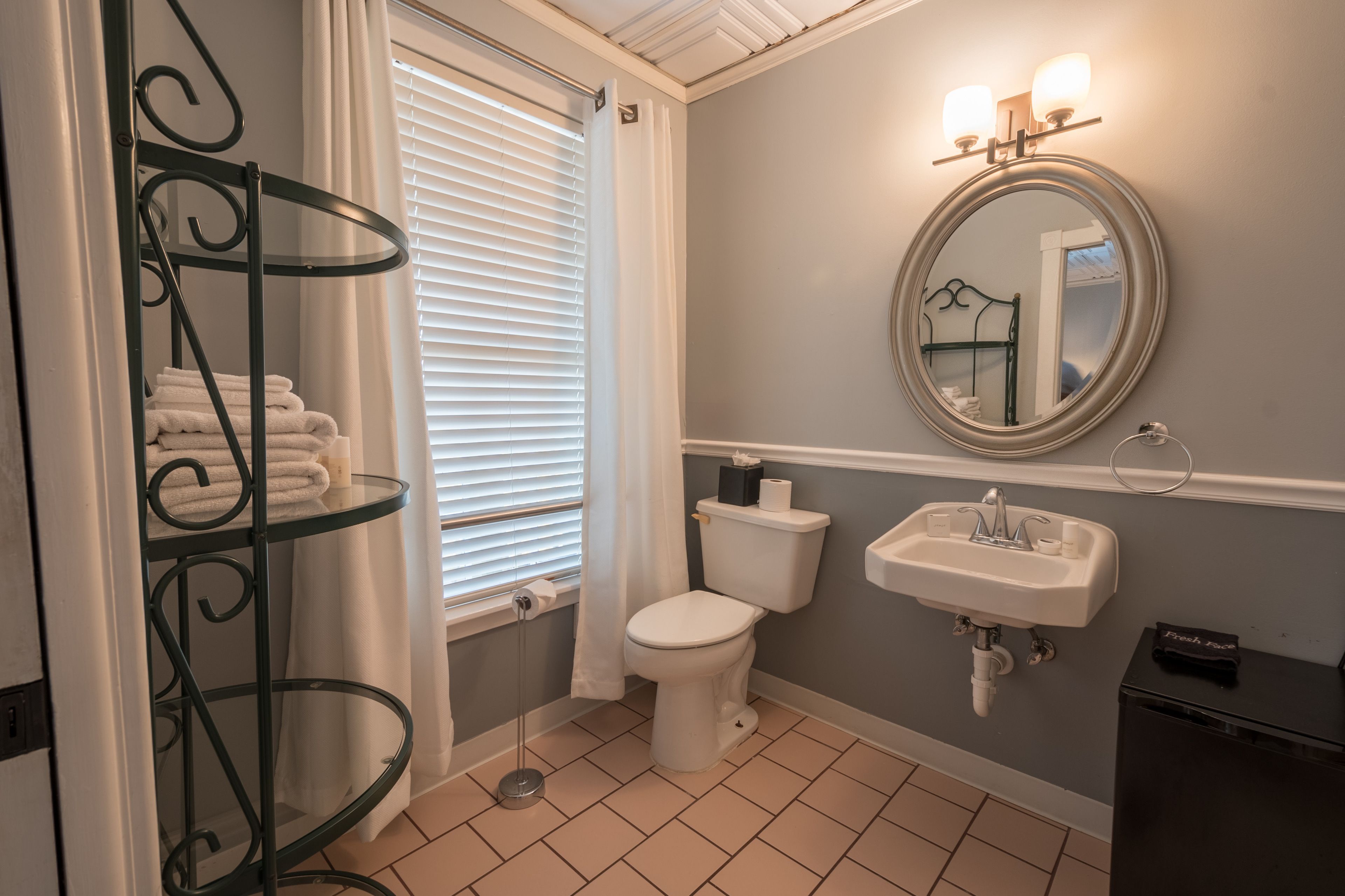 A bathroom with a toilet, sink, and a towel rack with folded towels.