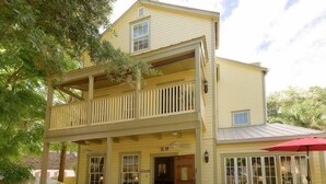 A two-story yellow building with a balcony, numbered 29, and a red umbrella. - Agustin Inn (St. Augustine)