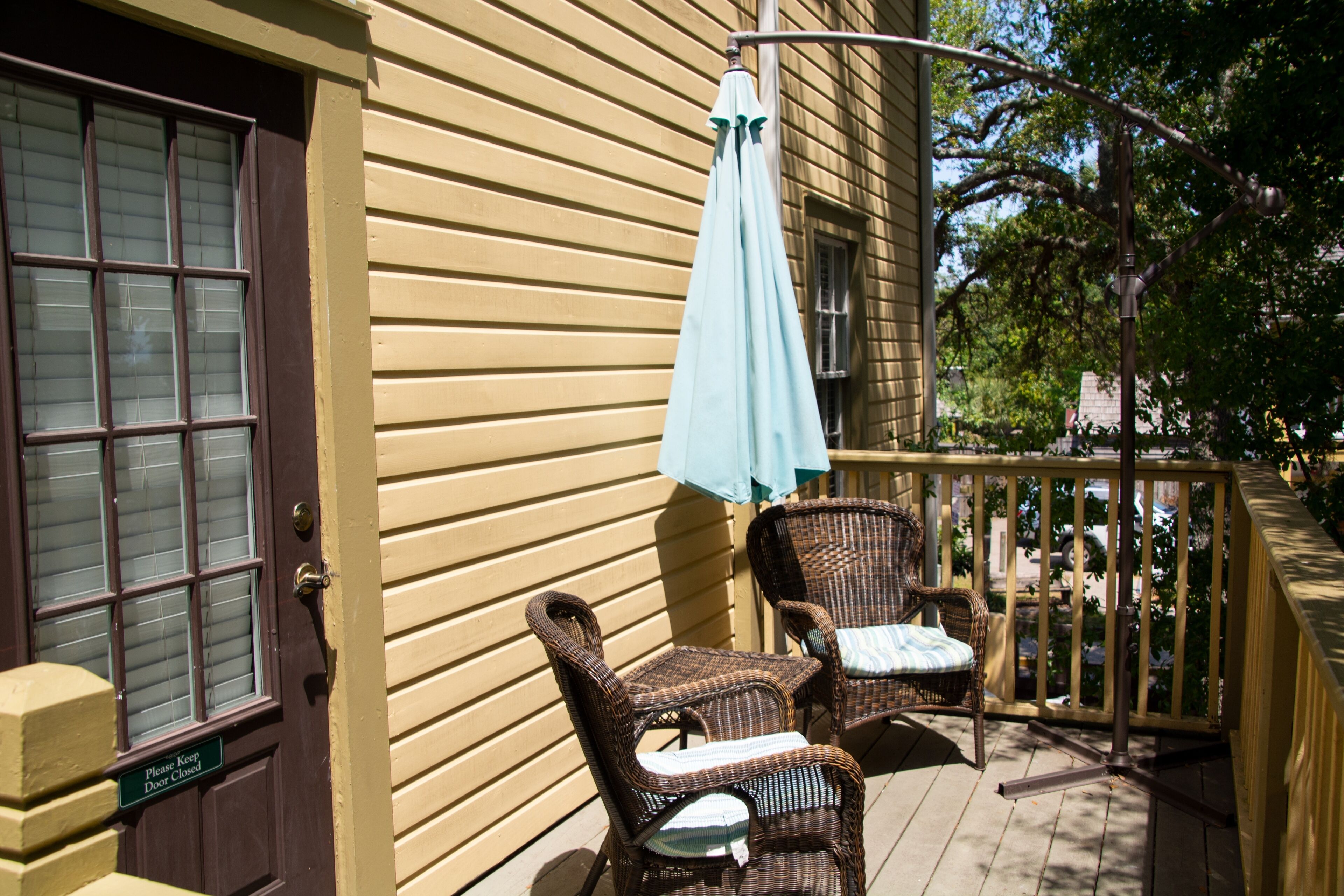 A wooden deck with wicker furniture and a closed door with a sign.