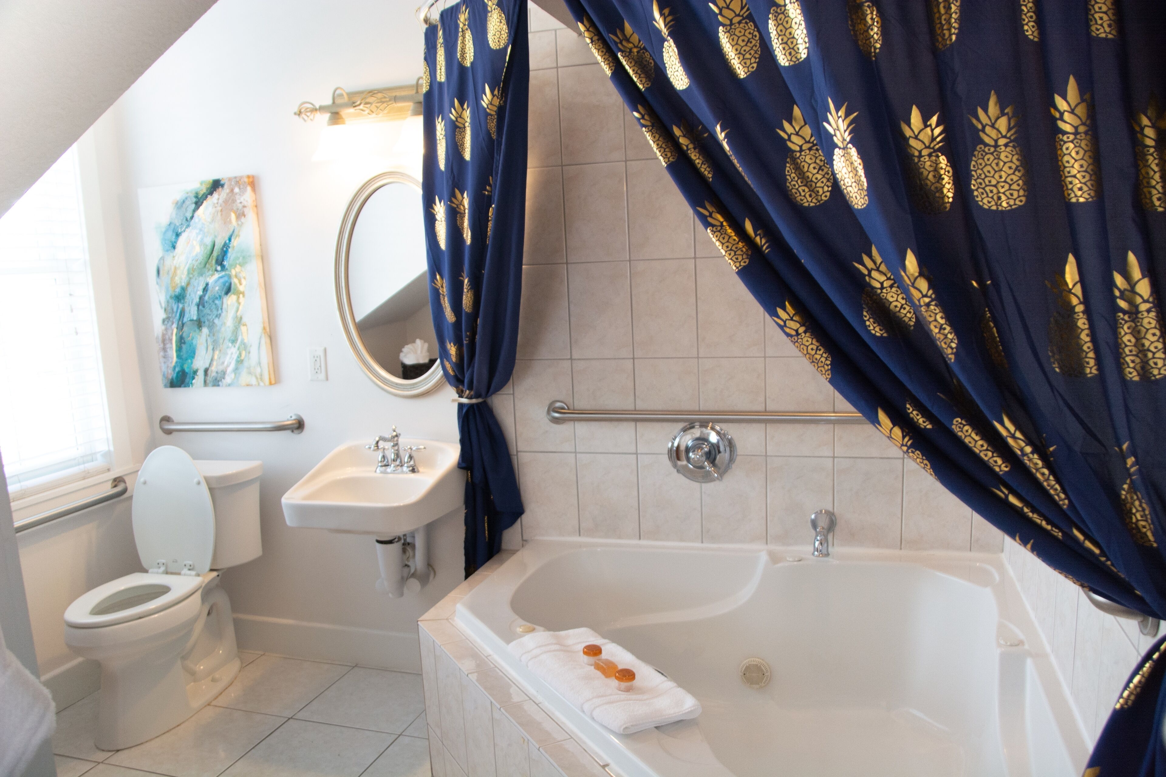 A bathroom with a white toilet, a sink, a bathtub, and a shower curtain with a pineapple pattern.