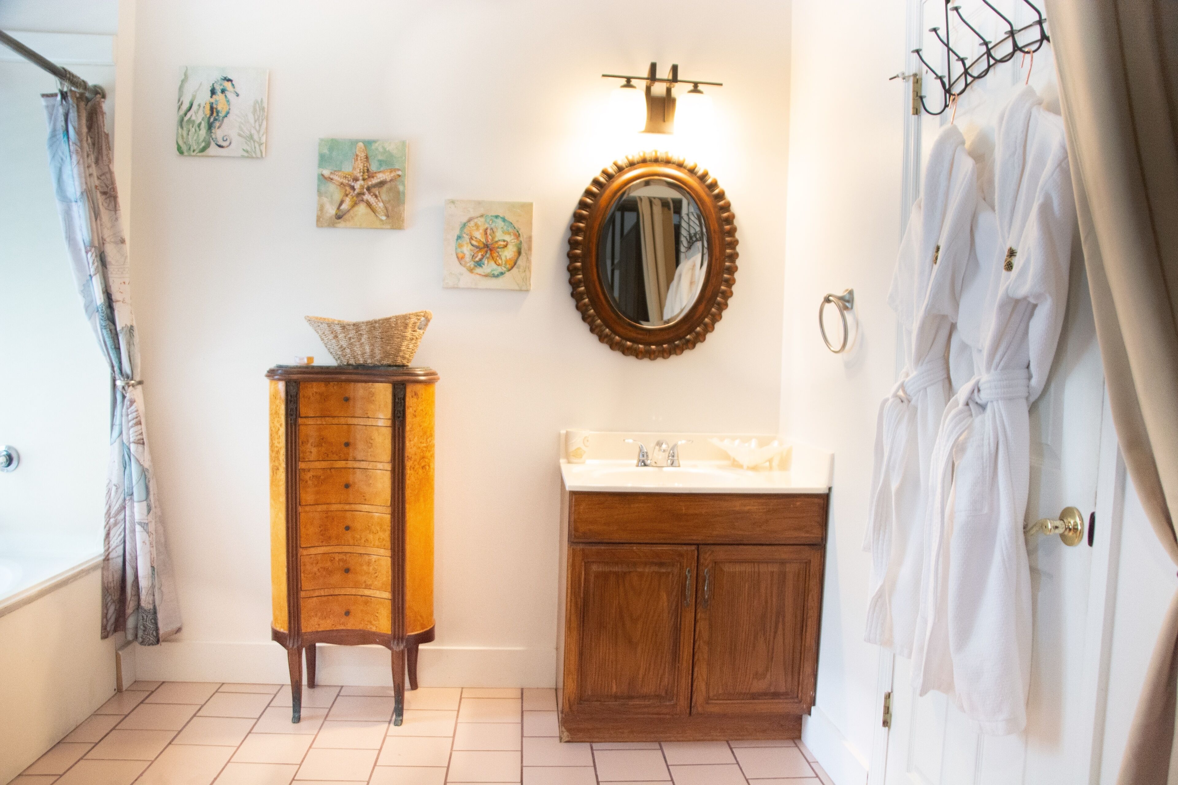 Een badkamer met een houten wastafelmeubel, een spiegel en kunst aan de muur.
