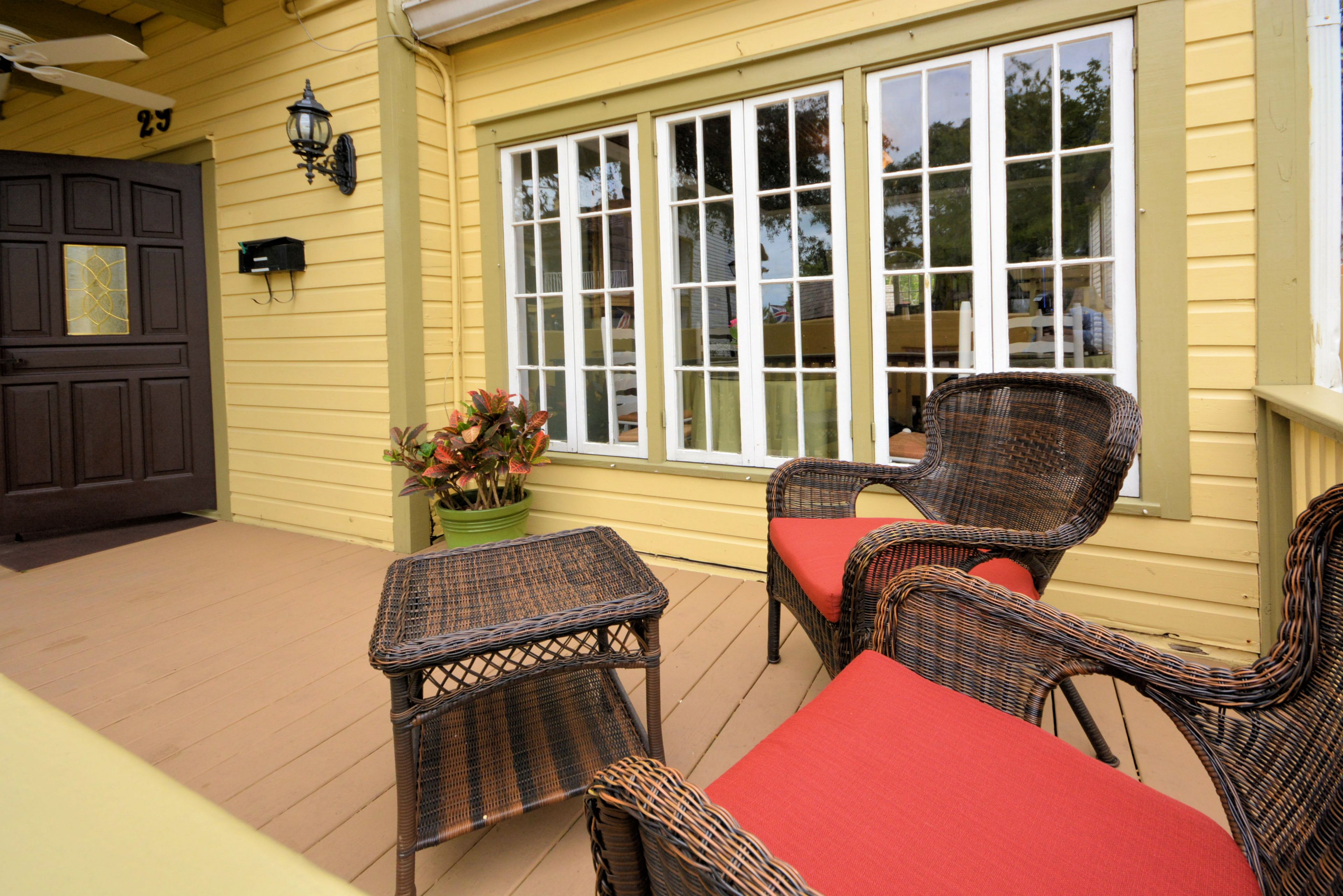 A covered patio with wicker furniture and a potted plant.