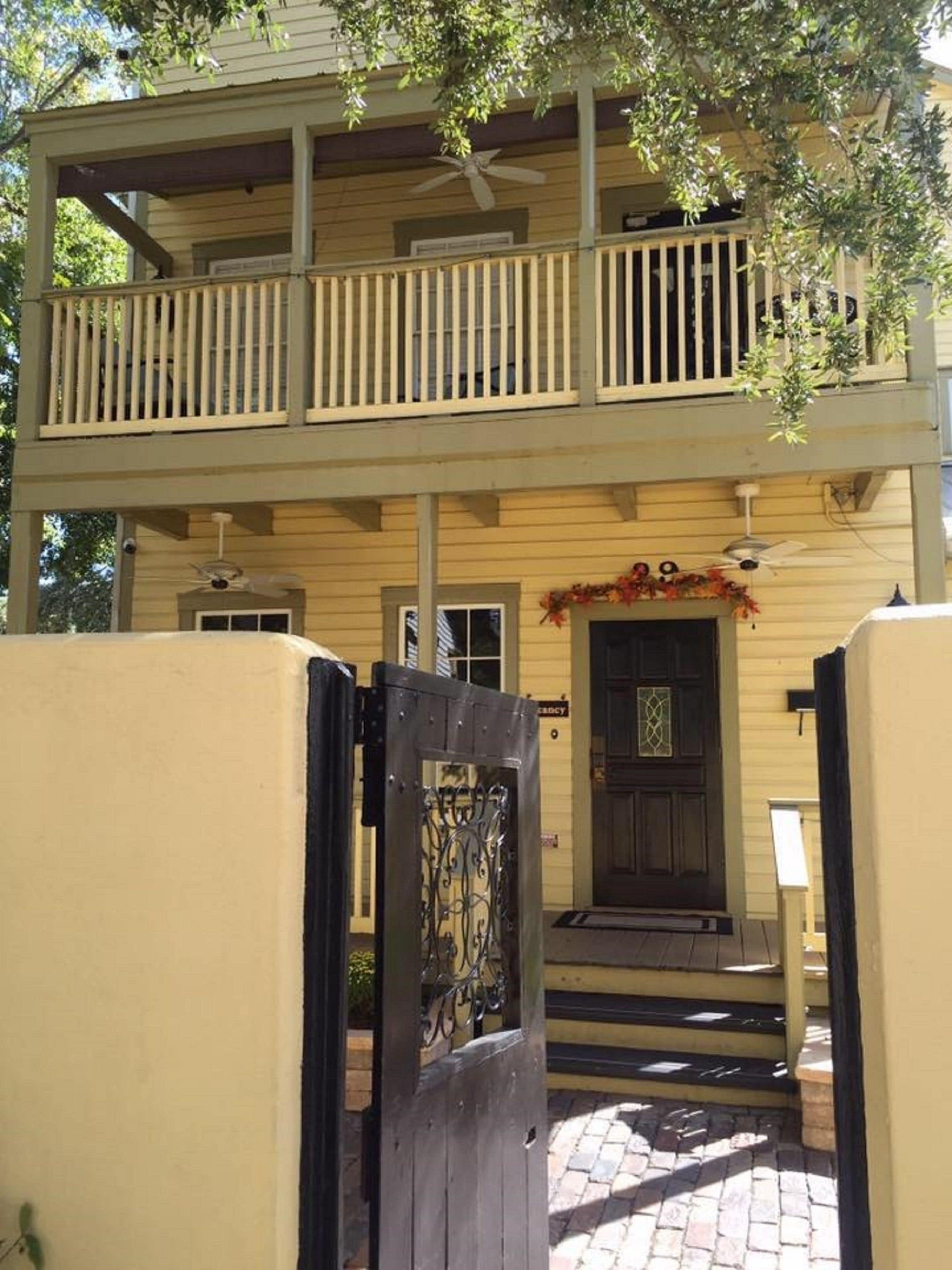 A two-story building with a balcony, a front door, and a staircase leading to the entrance.