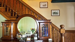 A wooden reception desk with a large mirror, glass-fronted cabinets, and framed pictures on the wall. - Agustin Inn (St. Augustine)