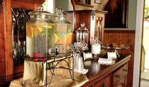 A bar area with a beverage dispenser, glasses, and a wooden counter.
