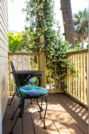 A wooden deck with a table and chairs, surrounded by a wooden fence and a tree with white flowers.