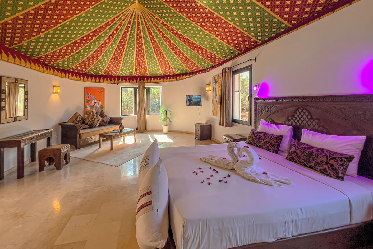 A spacious bedroom with a large bed, a ceiling fan, and a view of the outdoors.