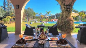 An outdoor dining area with a view of a pool and mountains. - Villa Marco Marrakech (Tameslouht)
