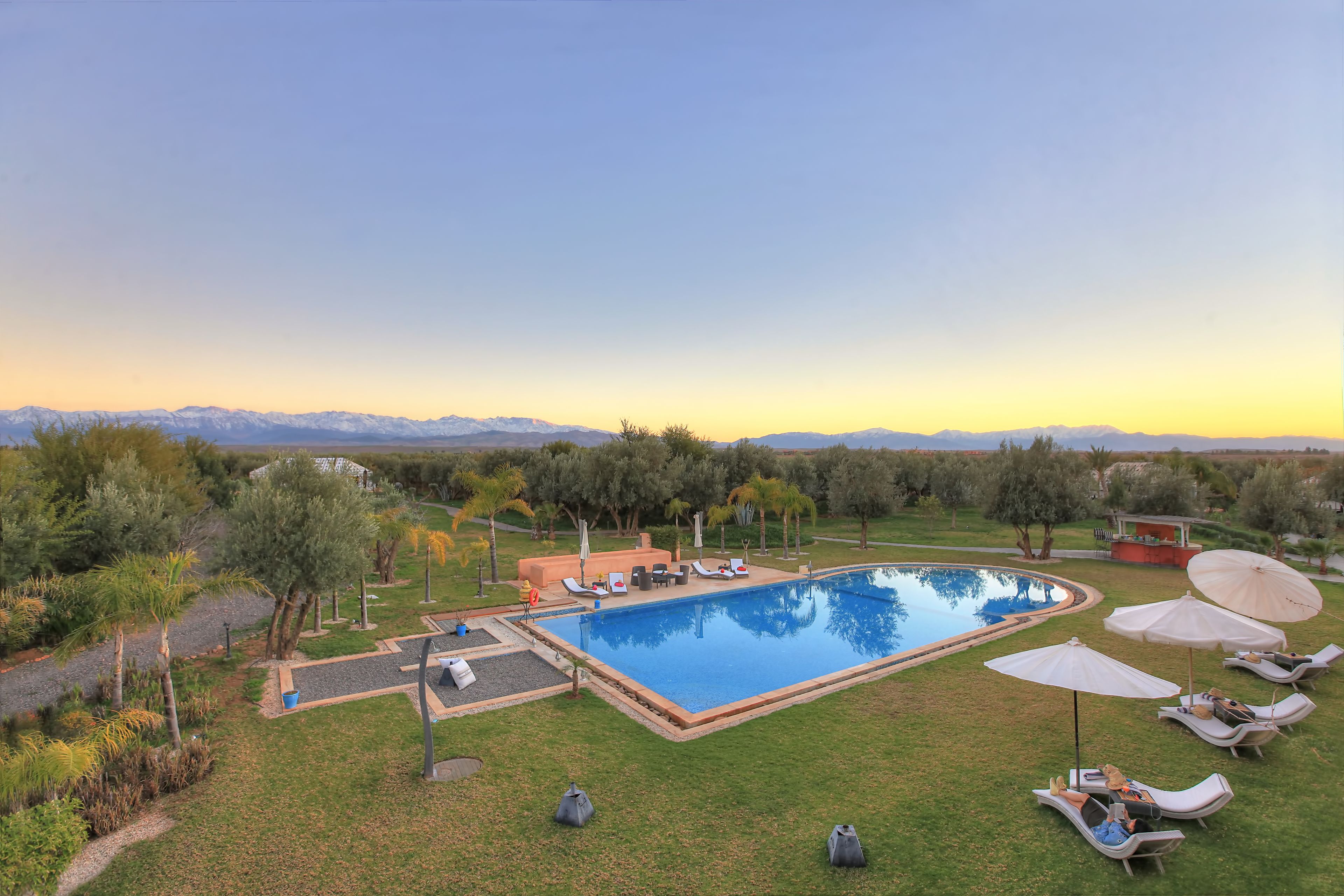 Una piscina al aire libre, sombrillas, sillones reclinables de piscina