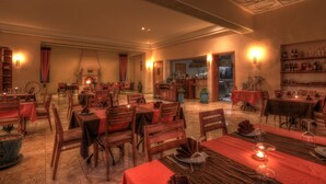 A spacious dining area with multiple tables and chairs, warm lighting, and a ceiling with a unique design. - Villa Marco Marrakech (Tameslouht)