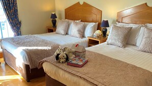 Una habitación de hotel con dos camas, cabeceros de madera y una mesita de noche con lámparas.