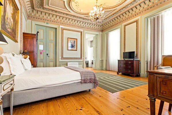 A spacious hotel room with a large bed, wooden floor, a chandelier, and a television. - Tesouro da Baixa by Shiadu (Lisbon)