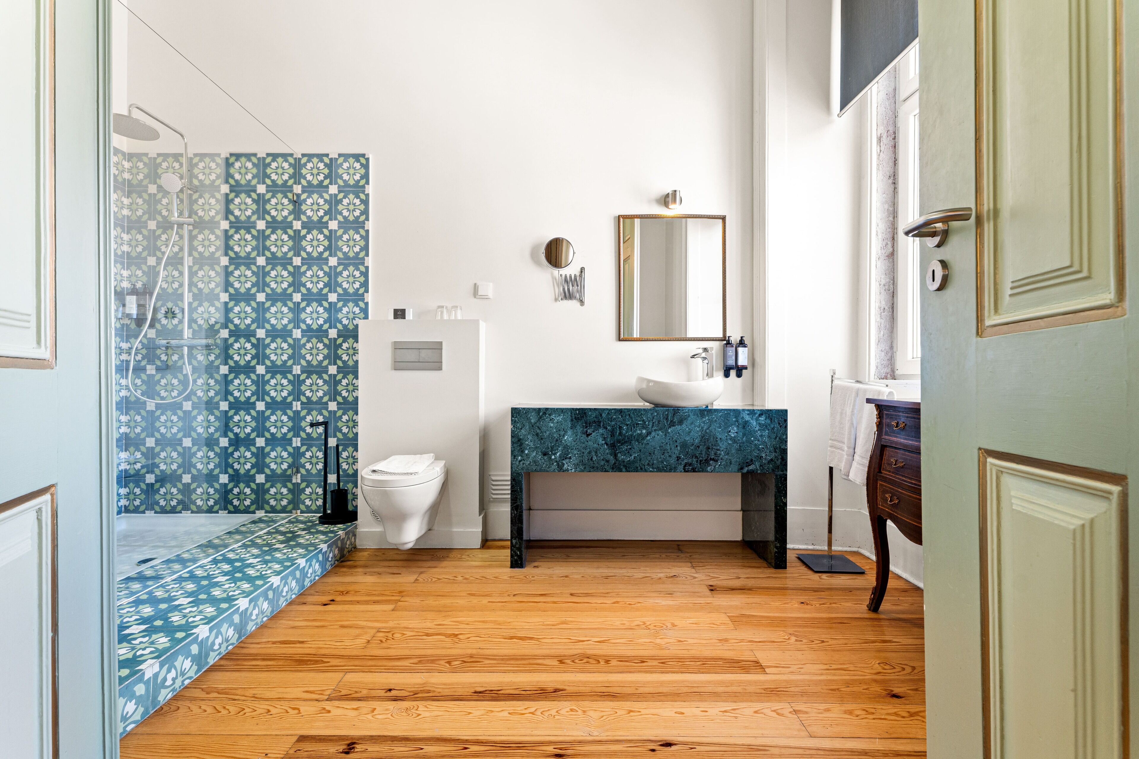 A bathroom with a shower, toilet, sink, and mirror.
