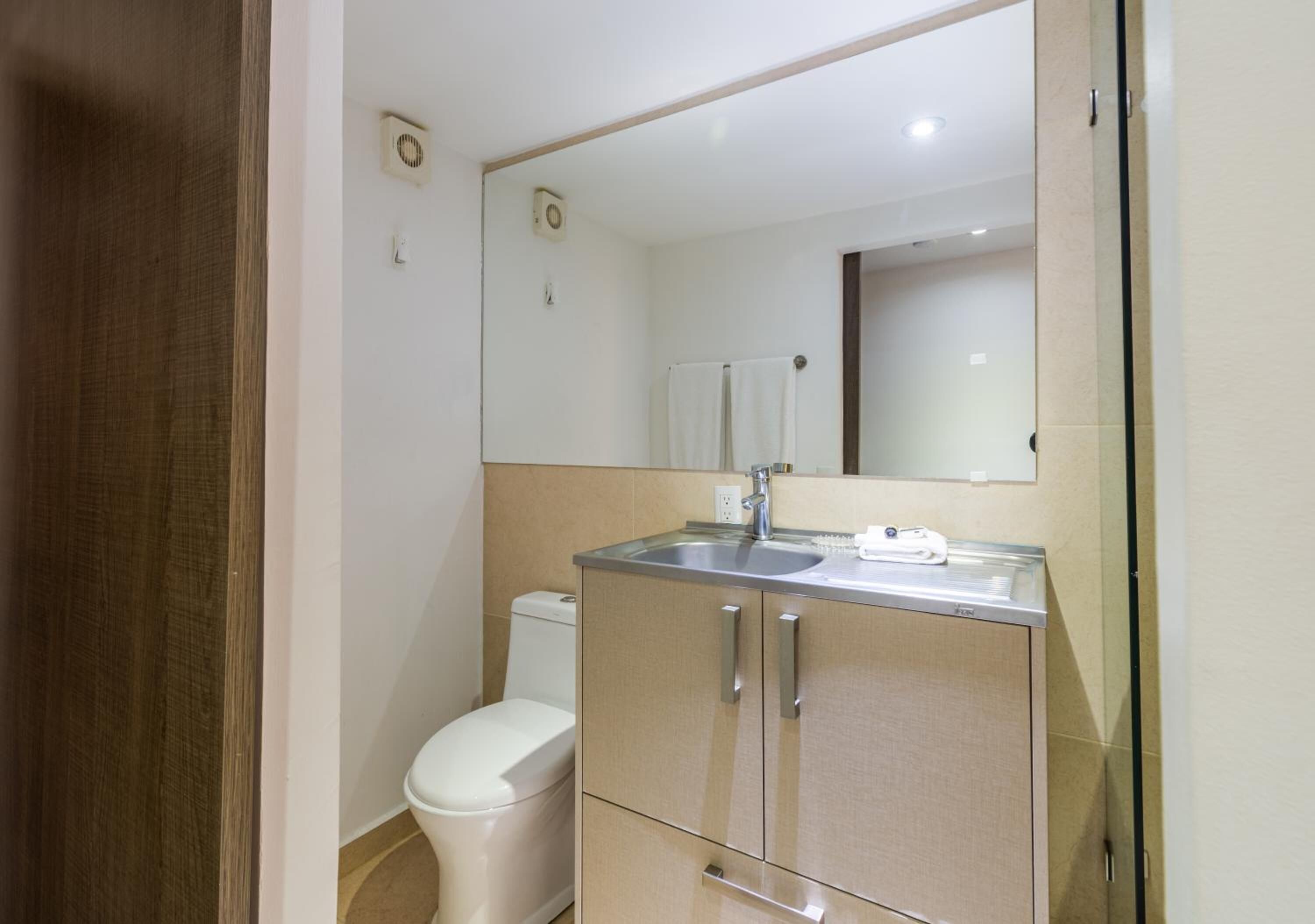 Un baño con inodoro, lavamanos y espejo.