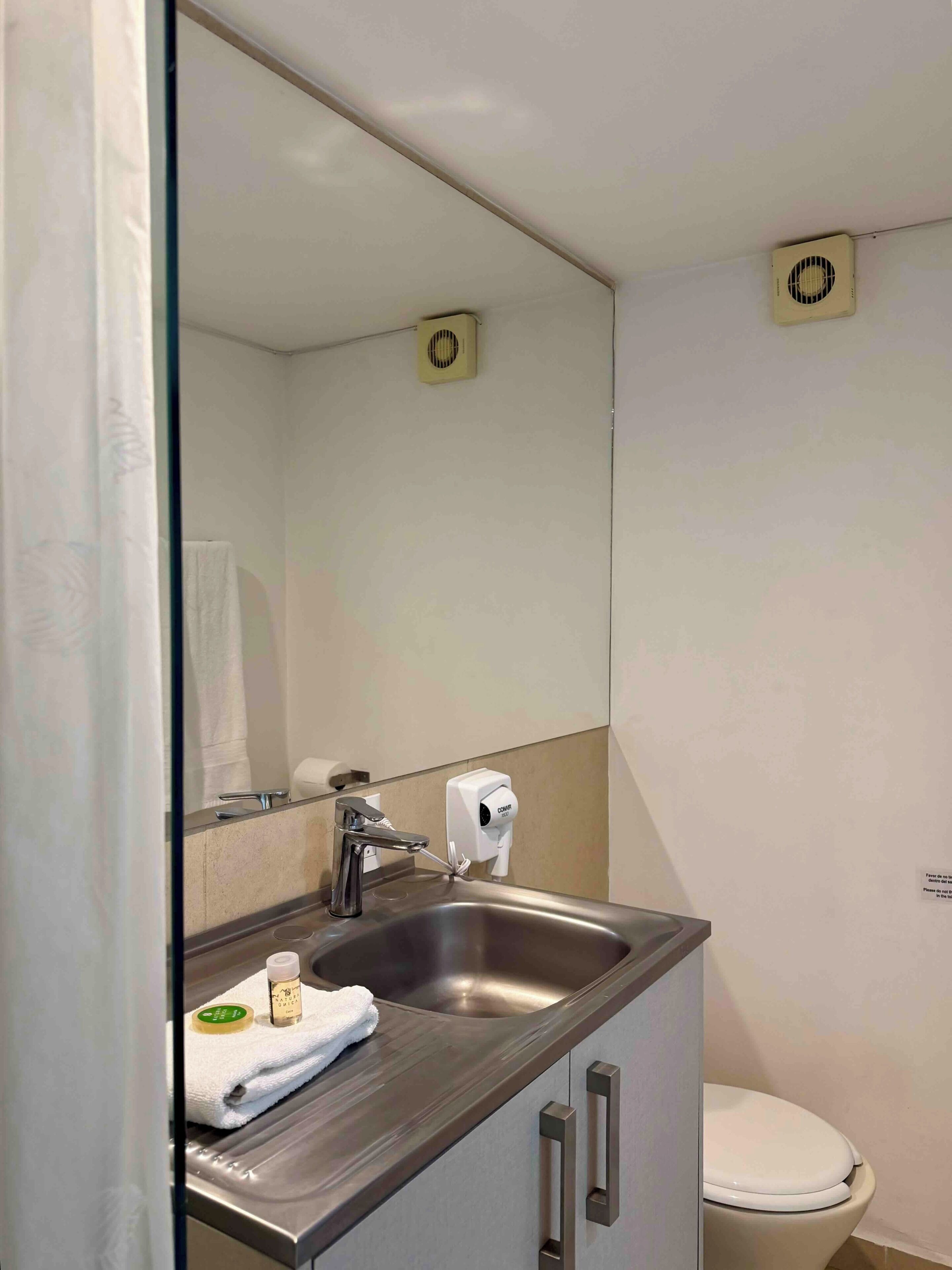 Un bagno con lavandino, specchio, servizi igienici e asciugatore di mani.