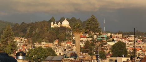 Un paisaje urbano con una iglesia blanca destacada en una colina, rodeada de edificios residenciales y árboles.