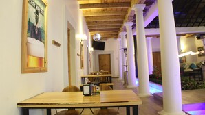 Un restaurante con vigas de madera y columnas blancas, que cuenta con una larga barra y zona de estar.