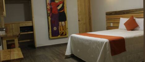 A bedroom with a bed, wooden headboard, and a painting on the wall.