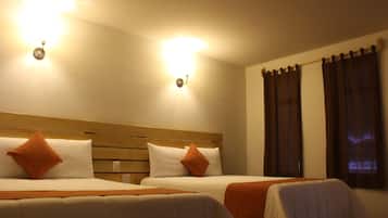 Two single beds with wooden headboards, white bedding, and orange pillows. There are two wall-mounted lights above the beds.