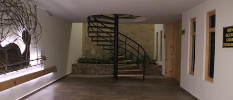A spacious hallway with a spiral staircase leading to a landing.