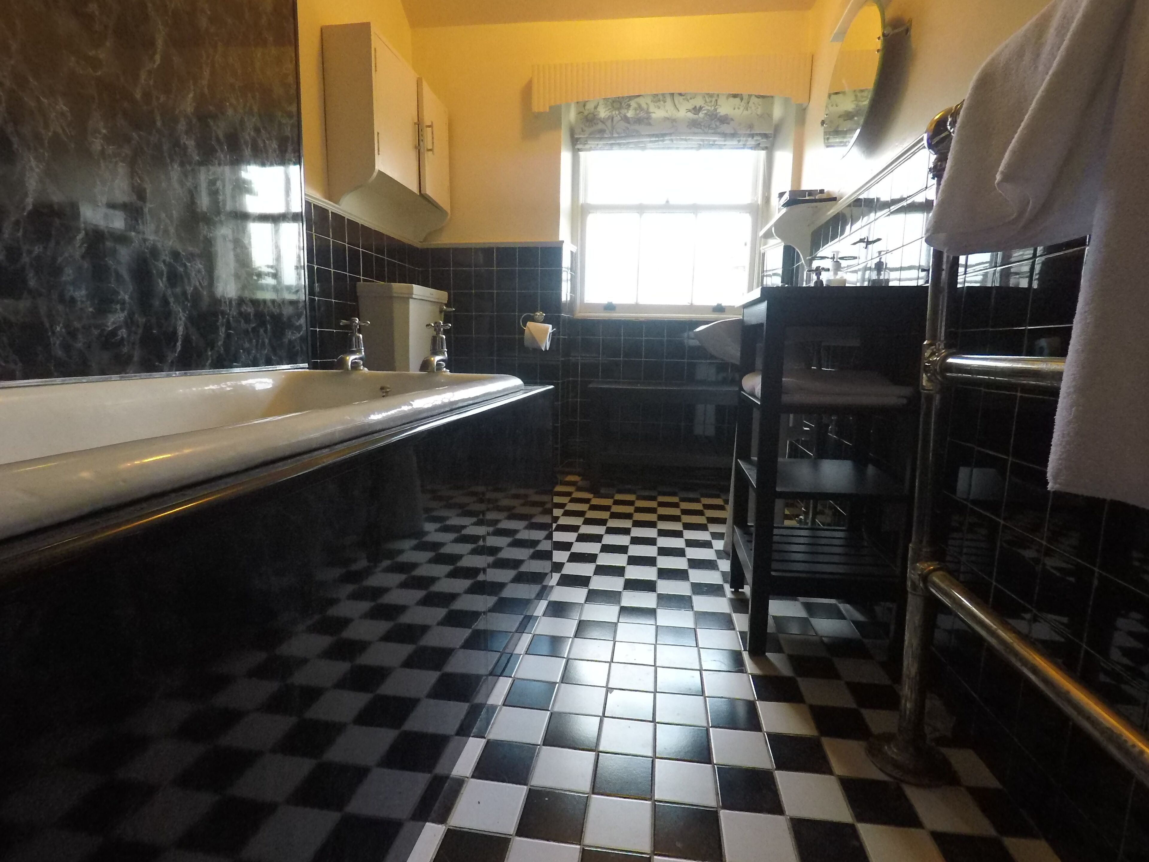 A bathroom with a checkered floor, a bathtub, and a towel rack.