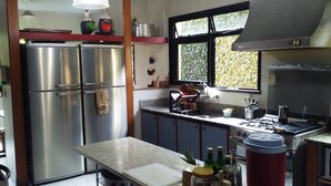 A kitchen with stainless steel appliances, a granite countertop, and a window with a view of greenery.