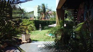 A courtyard with a statue, palm trees, and a building in the background.