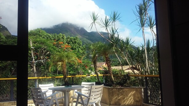 A balcony with a view of a mountainous landscape, outdoor seating, and a fence.