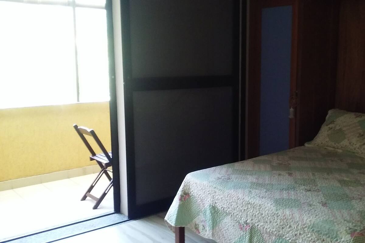 Een kamer met een bed, een stoel en een schuifdeur.
