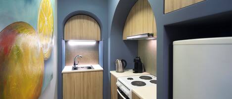 A compact kitchen with wooden cabinets, a sink, a stove, and a refrigerator.