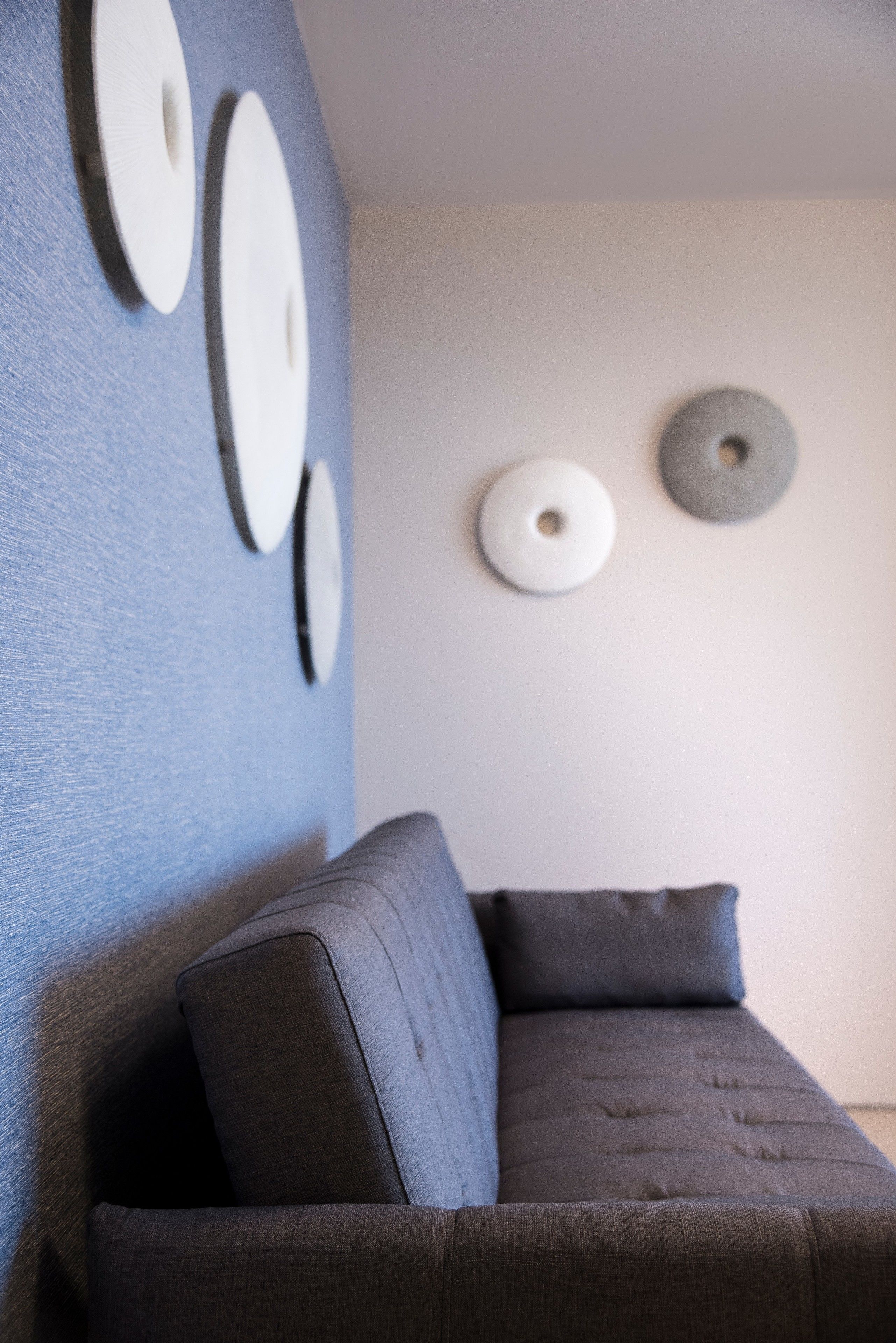 A modern living room with a dark gray sofa and wall-mounted circular decor.