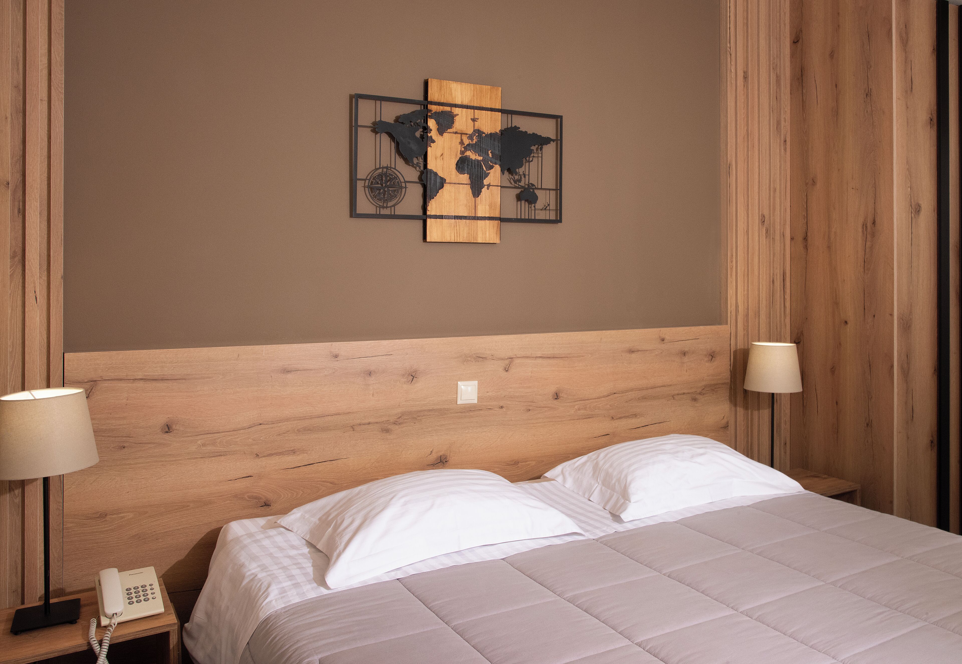 Un lit bien fait, avec du linge de lit blanc, une tête de lit en bois et deux lampes de chevet.