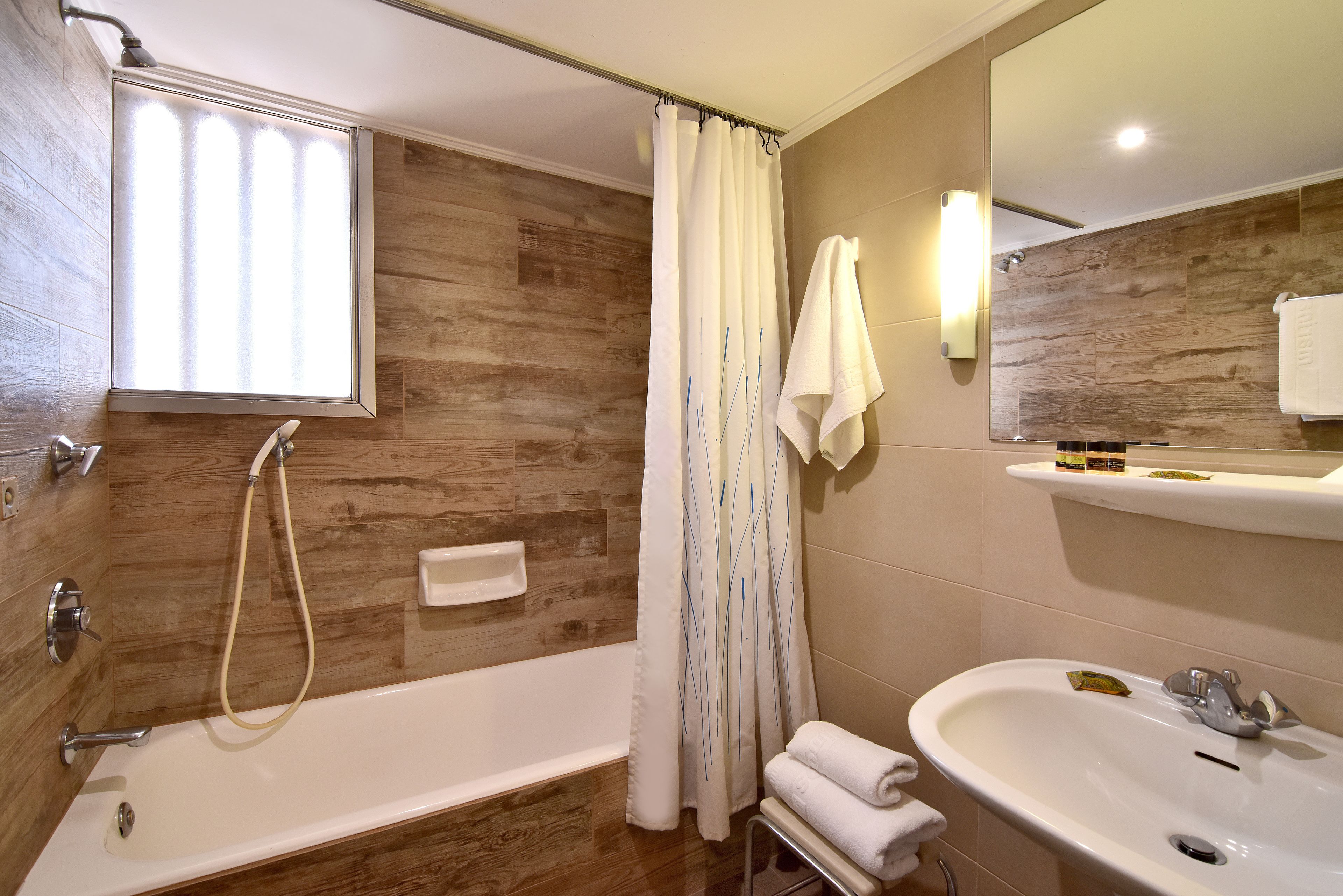 A bathroom with a bathtub, a sink, and a mirror.