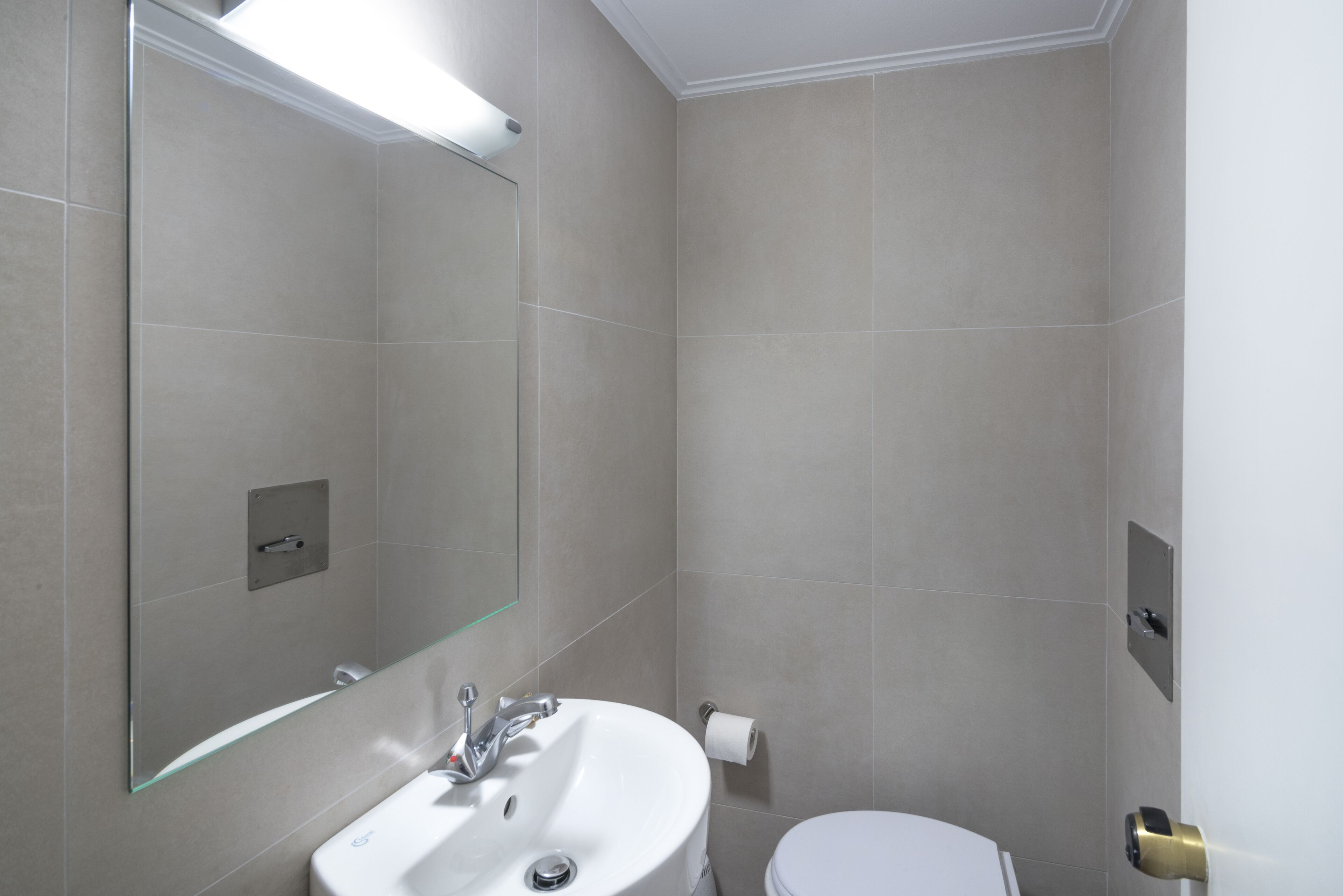 Une salle de bain avec un lavabo blanc, des toilettes et un miroir.