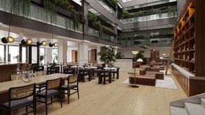 A spacious indoor area with multiple seating arrangements, including tables and chairs, and a large bookshelf. - Metcalfe Hotel Ottawa by Gray Collection (Ottawa)