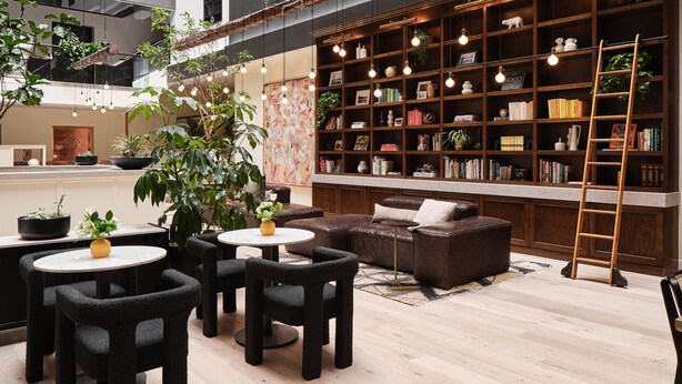 A modern indoor space with a central seating area, a bookshelf, and hanging lights. - Metcalfe Hotel Ottawa by Gray Collection (Ottawa)