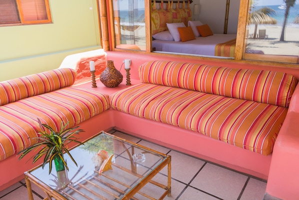 A pink and orange striped sofa with a glass coffee table and a vase with a plant.