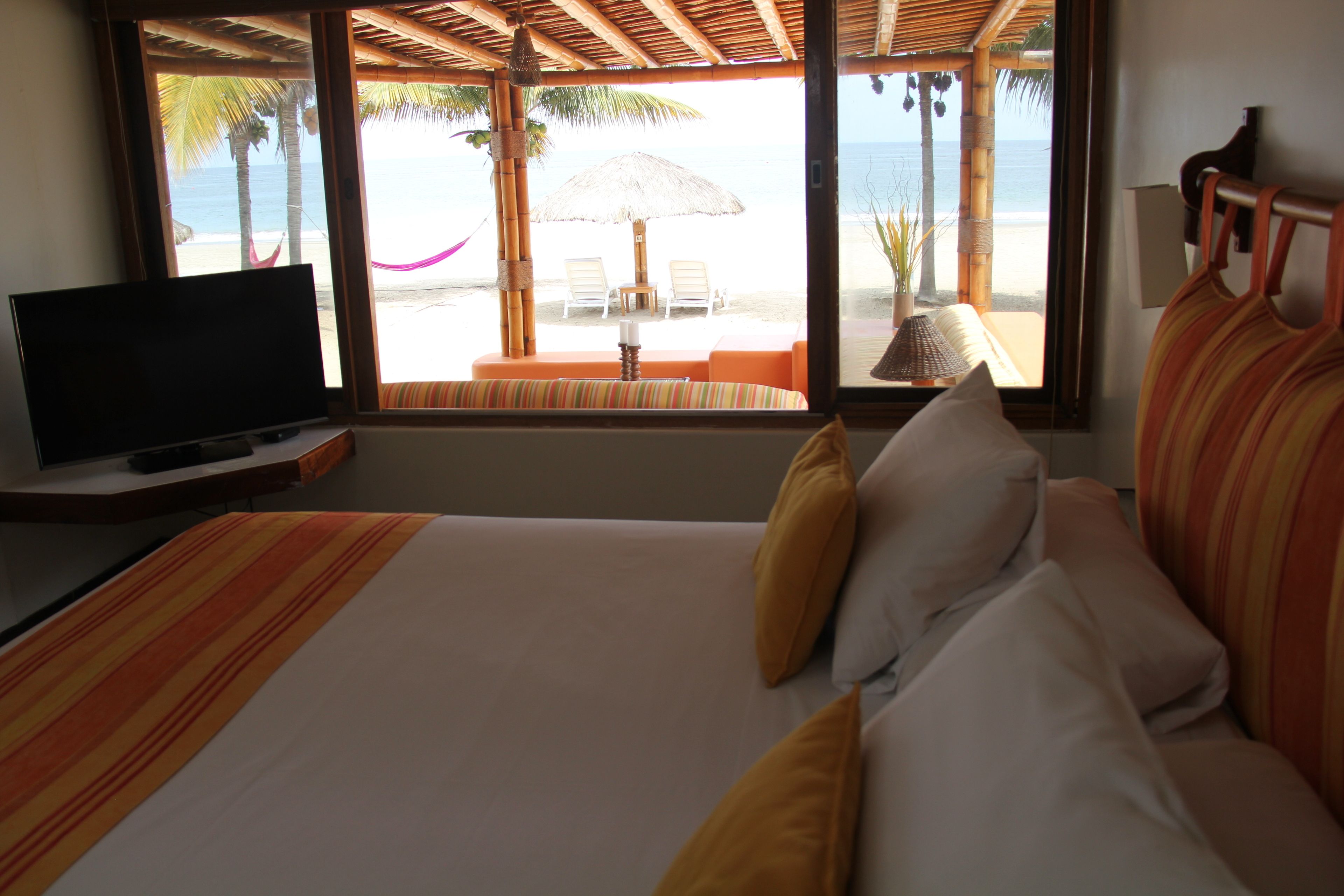 Habitación de hotel con cama, televisión y vista a la playa.